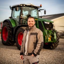 Commercieel contactpersoon Sandoa Alashqar naast een landbouwmachine op het bedrijfsterrein